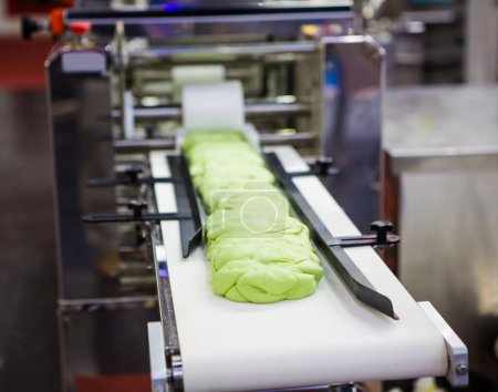 Dough on conveyor preparing for steamed stuffed bun.