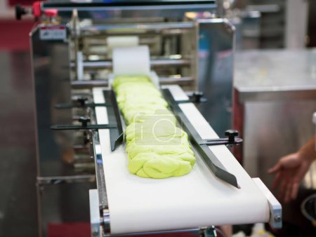 Dough on conveyor preparing for steamed stuffed bun.