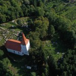 Aerial view of a whitewashed church and graveyard. Drone shot of a medieval landmark in Bikfalva, Bicfalau, Szeklerland, Romania