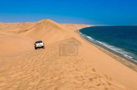 Safari trip by car through sand dunes on ocean shore of Sandwich harbour, extreme travel adventure on Atlantic coast of Namibia, South Africa