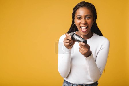 Téléchargez les photos : Photo of happy excited crazy smiling woman playing videogames addicted to playstation isolated on yellow colour background - en image libre de droit
