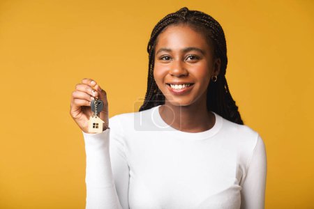 Foto de Young happy overjoyed woman holding keys of apartments and rejoicing isolated on yellow background. People lifestyle concept - Imagen libre de derechos