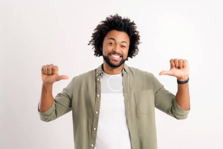 Téléchargez les photos : Attrayant 30s afro-américain homme pointant pouces lui-même fier gagnant isolé sur blanc, positif fier bouclé gars avec blanc dents sourire offre de choisir sa candidature - en image libre de droit
