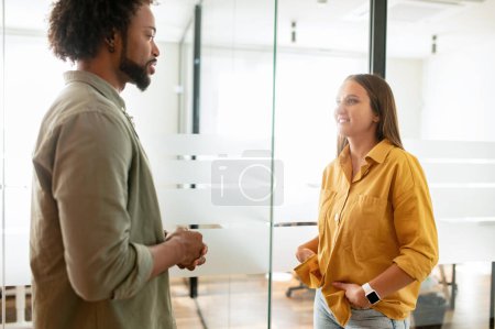 Photo for Pair of friendly colleagues work in office. Young business people are talking in modern hallway - Royalty Free Image