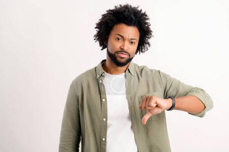 Photo for I do not like it. Serious unhappy African-American guy showing thumb down standing isolated on white, disagree with you, man in casual wear unsatisfied, discontent, uncontented - Royalty Free Image
