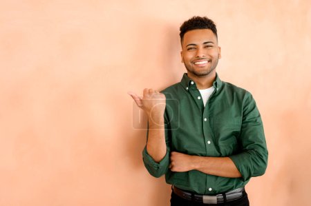 Photo for Happy indian student with thumb aside, salesman indicating advertising, recommending novelty, arab young man in formal wear presenting deal, promotion, isolated - Royalty Free Image
