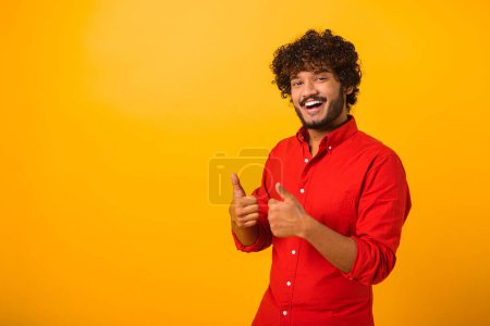 Photo for Portrait of man with beard standing with thumbs up, like gesture, demonstrating approval and agree with suggestion. Indoor studio shot isolated on orange background - Royalty Free Image