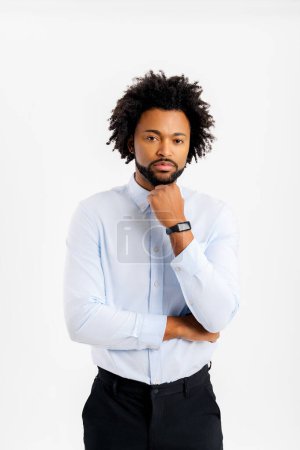 Téléchargez les photos : Sérieux coûteux jeune homme d'affaires afro-américain trentenaire portant chemise blanche classique debout mis appui à la main sur le menton regardant de côté isolé sur fond de mur de couleur rouge vif portrait studio - en image libre de droit