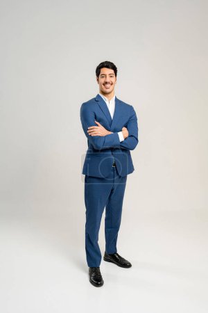 Photo for Standing tall and exuding confidence, this young businessman in a blue suit presents a classic image of professionalism and reliability, ideal for corporate branding and representation, full length - Royalty Free Image