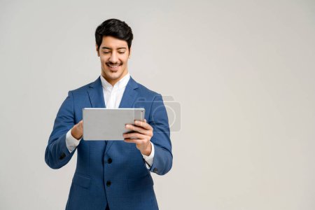 Photo for The professional stands with a tablet, his smile and attentive look reflecting an individual adept in digital tools, perfect for representing digital marketing or business innovation, isolated - Royalty Free Image