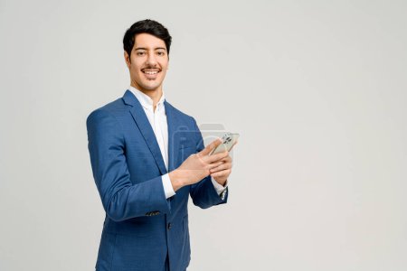 Photo for Cheerful businessman in blue suit holds a smartphone, his face radiating satisfaction, perhaps from a successful deal or receiving good news. This photograph symbolizes positive business communication - Royalty Free Image