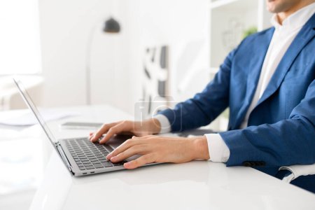 Photo for Cropped photo of hands of male office employee mid-typing on a laptop, sitting in office space. The image illustrates the day-to-day engagement and concentration that business tasks require. - Royalty Free Image