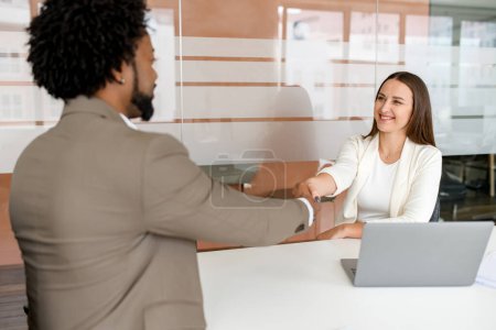 Photo for A professional handshake viewed from behind the man, capturing the moment of agreement or partnership in a bright office setting - Royalty Free Image