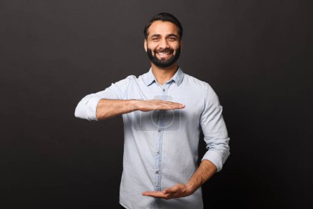 The Indian businessman makes a gesture with his hands, framing an invisible concept, set against a neutral background to suggest innovation and conceptual thinking in business
