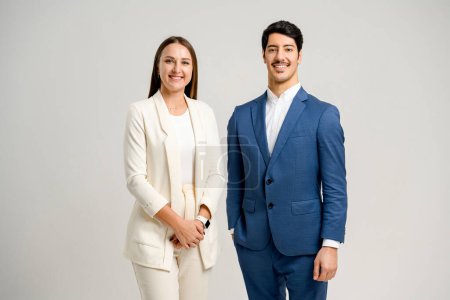 Photo for A businesswoman and businessman, dressed in light beige and sharp blue suits, stand side by side, presenting a united and professional image reflective of partnership and corporate equality. - Royalty Free Image