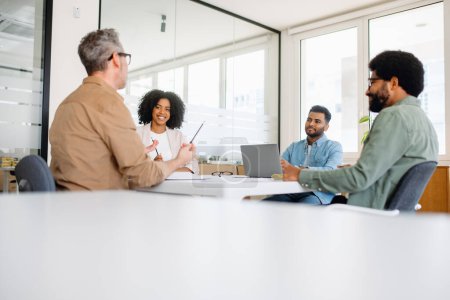 Photo for A lively team discussion unfolds in a modern office, where diverse colleagues share ideas with confidence, planning together, signifying a dynamic and inclusive workplace - Royalty Free Image