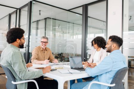 Photo for A diverse group of professionals is gathered around a meeting table in a contemporary office space, actively engaged in a productive brainstorming session. - Royalty Free Image