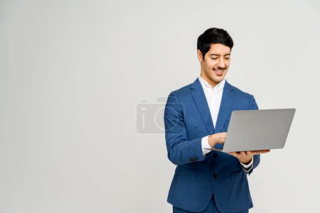 Businessman in blue suit is using laptop, a depiction of modern professionalism and digital engagement, concept of mobile business, suggesting ease of technology use and successful work outcomes