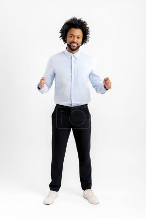 Photo for Advertising concept. Excited happy African-American guy demonstrating size of product with hands, measuring empty space, over white background. Black man holds imagined object, something in palms - Royalty Free Image