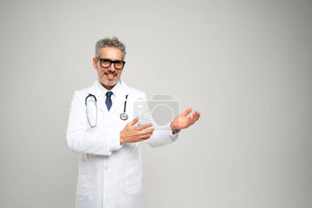 Ein reifer Arzt mit einem warmen Lächeln streckt seine Hand in einer einladenden Geste vor hellem Hintergrund aus und beschwört ein Gefühl der Freundlichkeit und Offenheit herauf, das für Patientenbeziehungen lebenswichtig ist..