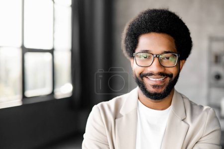 Photo for Young Brazilian businessman with a charming smile stands confidently, looking at the camera with friendly smile. The minimalist background emphasizes his modern approach to business and connectivity - Royalty Free Image