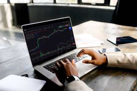 Geschäftsmann Händler analysiert Finanzdiagramme auf Laptop, was auf eine gründliche Beurteilung der Markttrends und Business Analytics. Die entscheidende Rolle der Datenanalyse bei der strategischen Entscheidungsfindung