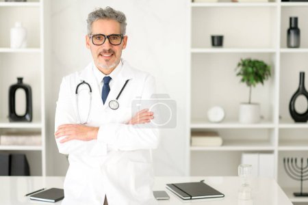 Senior doctor stands with arms crossed in office, indicating a blend of traditional and modern medical practices. He radiates experience and welcoming atmosphere, ideal for trusted healthcare setting