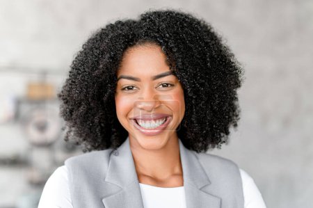 A cheerful African-American businesswoman in professional attire beams with joy, providing a personal touch to a business setting, perfect representation of modern businesswomen