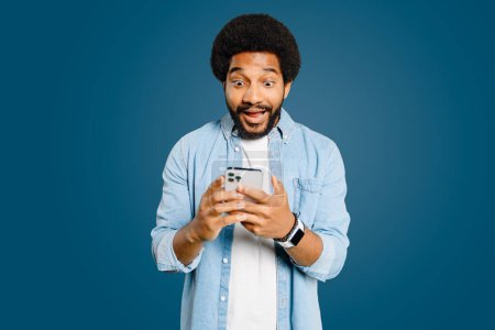 Young man looks surprised and excited using a smartphone, embodying a spontaneous moment of receiving unexpectedly good news, perfect for representing instant communication and its impact on emotions