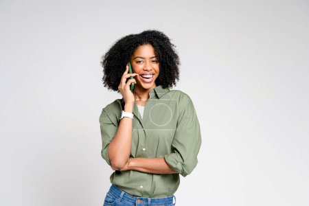 This image captures a radiant African-American woman with a captivating smile as she talks on her smartphone, conveying a sense of friendly communication