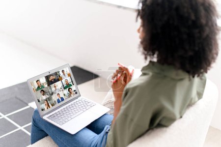 Photo for This African-American woman participates in a virtual meeting from her laptop, showcasing the modern way of collaborative work in a homely setting. - Royalty Free Image