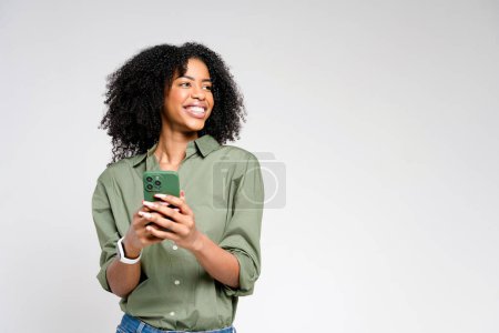 Die Frau ist in einem aufrichtigen Moment abgebildet und blickt mit einem natürlichen und entspannten Lächeln von ihrem Handy weg, was ein Gefühl der Leichtigkeit und authentischen Interaktion hervorruft.