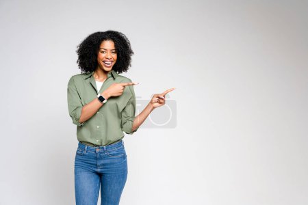 With an inviting presentation, this African-American woman in a smart-casual outfit points to an invisible product, perfect for advertising and promotion.