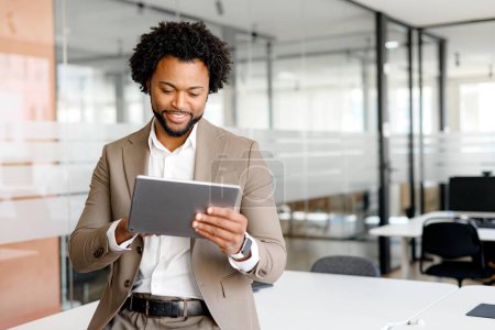 African-American young businessman looking at his tablet with an expression of pleasant surprise. This shot perfect for conveying concepts like real-time data analysis, business agility, e-commerce