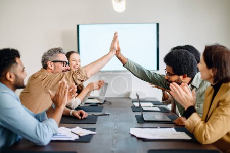 Photo for A team celebrates a shared success with high fives, encapsulating a moment of achievement and unity in a contemporary office space, reflect a positive and dynamic work culture. - Royalty Free Image
