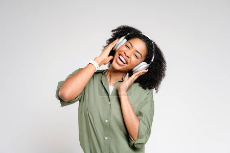 Foto de Una vibrante dama afroamericana es capturada en medio de la danza, su teléfono inteligente en la mano, disfrutando de sus canciones favoritas, mostrando un momento de alegría sin preocupaciones y aprecio por la música. - Imagen libre de derechos