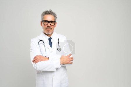 A senior doctor presents a strong and assuring presence, arms folded with a serious expression, against a neutral background, epitomizing the professional and determined nature of medical care.