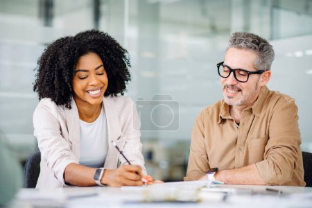 A Brazilian businesswoman in a beige blazer shares ideas with a male colleague, capturing the essence of a friendly and supportive work atmosphere where collaboration and mutual respect are valued