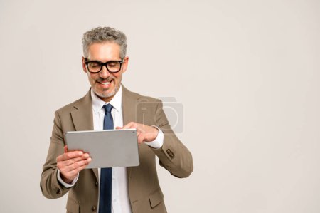 Routinierter Geschäftsmann mit grauen Haaren und Brille, der selbstbewusst ein Tablet bedient, sein Lächeln suggeriert Leichtigkeit mit Technologie, die die Kluft zwischen traditionellem Geschäftssinn und modernen digitalen Trends überbrückt