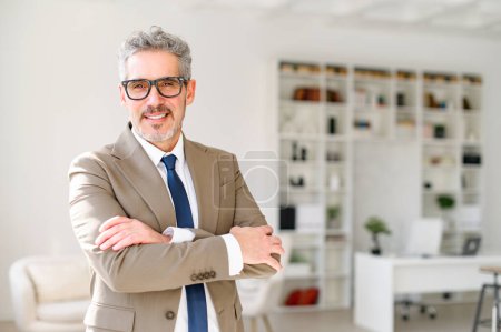 A charismatic senior entrepreneur stands in a modern office space, arms crossed, smiling confidently at the camera, embodying a blend of experience and approachability, focus on leadership and success