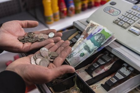 Téléchargez les photos : Mains d'un homme comptant de l'argent colombien à un comptoir de caisse - en image libre de droit