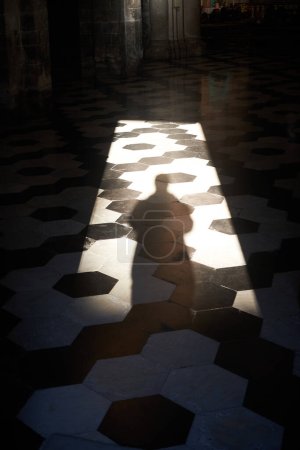 La silueta del hombre se encuentra ante una antigua iglesia, su enigmático reflejo.