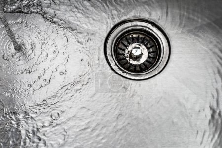 Foto de Running water drains down a stainless steel sink - Imagen libre de derechos