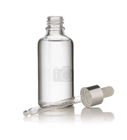 Foto de Caída de una pipeta en una botella cosmética, aislada sobre fondo blanco - Imagen libre de derechos