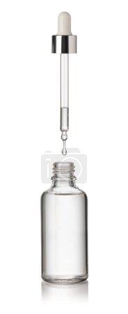 Téléchargez les photos : Une goutte tombe d'une pipette dans une bouteille cosmétique, isolée sur fond blanc - en image libre de droit