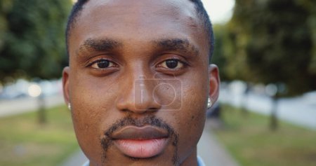 Photo for Front view of concentrated attractive young african american with stylish mustache which posing on camera on the background of urban alley with green trees - Royalty Free Image