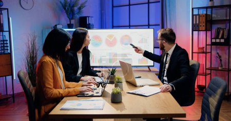 Photo for Business concept where attractive confident industrious skilled man and woman office managers working together in evening office and discussing presentation on digital whiteboard - Royalty Free Image