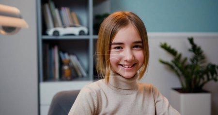 Photo for Close up of cute smart caucasian smiling girl loking at camera, indoors. Beautiful girlsitting at table at home with a laptop looks at camera and smiling - Royalty Free Image