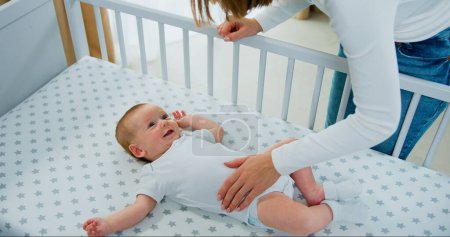 Téléchargez les photos : Vue de dessus. Maman jouant à adorable nouveau-né sur le lit souriant et le bonheur à la maison. Joyeux bébé garçon sourire et rire bruyamment. - en image libre de droit