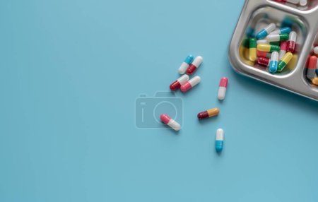 Foto de Vista superior de las píldoras coloridas de la cápsula antibiótica en una bandeja y fondo azul. Resistencia a los antibióticos. Drogas antimicrobianas. Medicamentos recetados. Industria farmacéutica. Salud y medicina. - Imagen libre de derechos